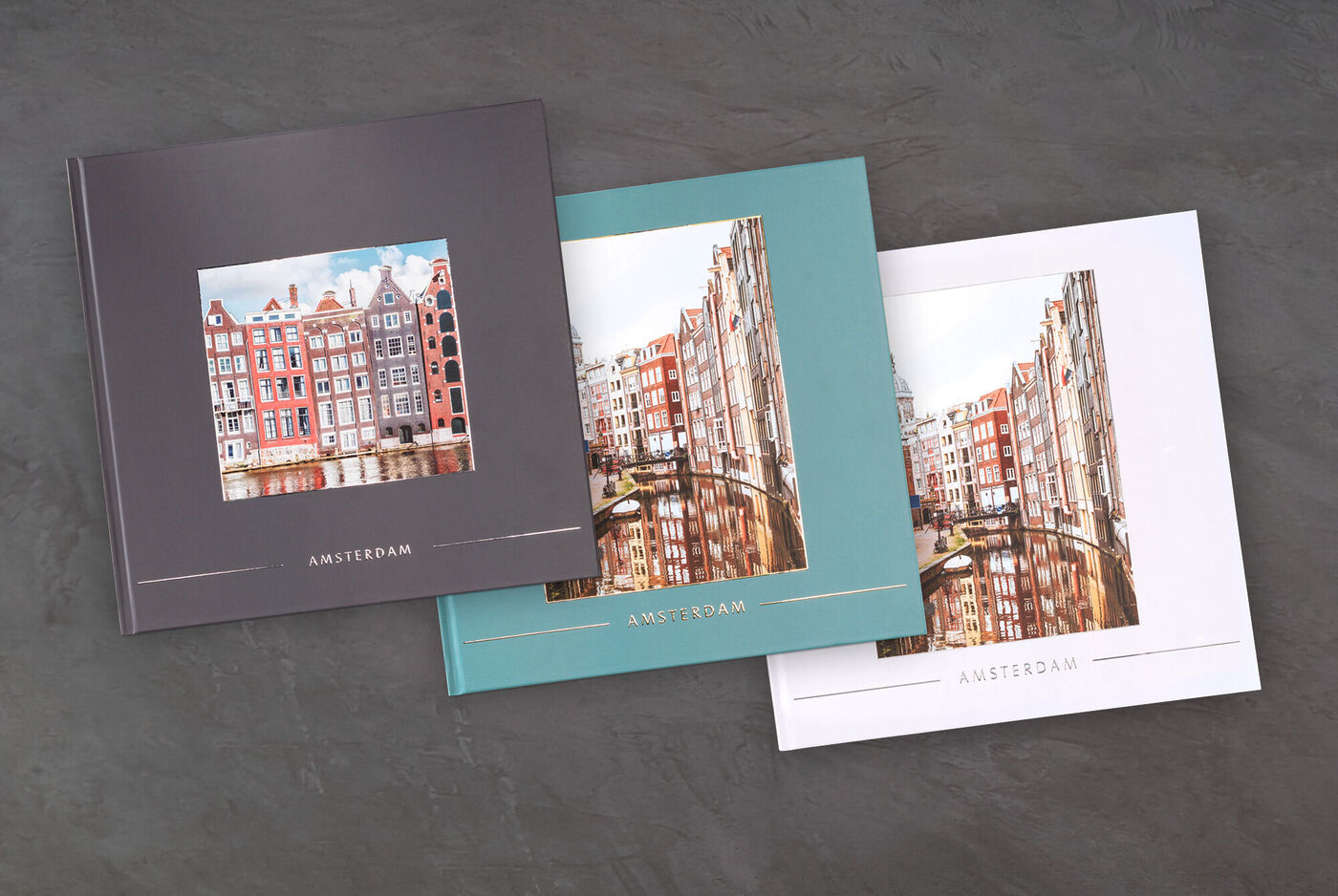 Tre forskellige CEWE fotobøger med billeder fra Amsterdam, hver med et andet farveskema.