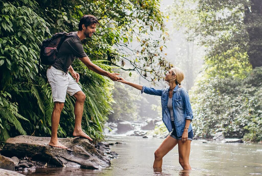 Et par nyder et øjeblik ved floden og holder hinanden i hånden.